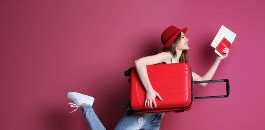 kobieta z czerwoną walizką i biletem spieszy się na samolot