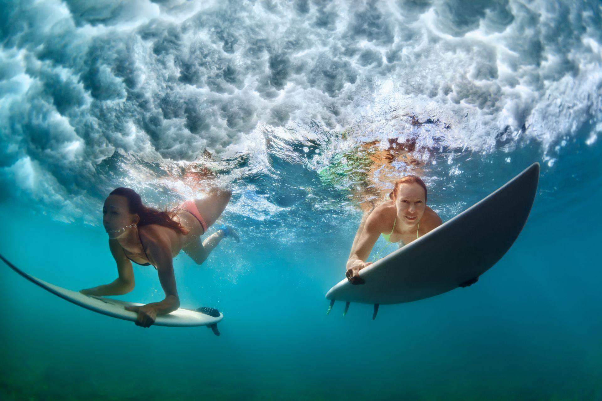 młode dziewczyny nurkujące z deskami do surfingu