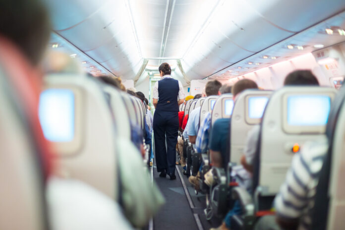 stewardessa idąca alejką między rzędami w samolocie