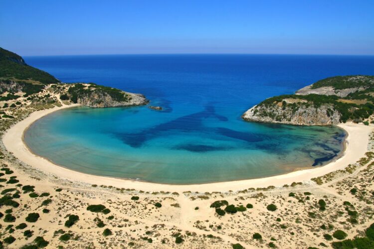 zatoka w kształcie greckiej litery omega z piaszczystą plażą i wieloma odcieniami błękitu