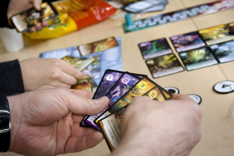 karty trzymane przez osoby grające w grę planszową