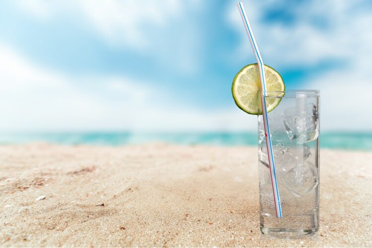 szklanka ze słomką i cytryną na plaży na tle morza