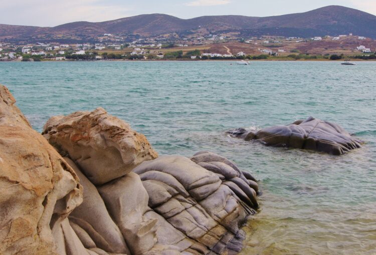 dziwne w kształtach skały wystające z morza na tle wzgórza 