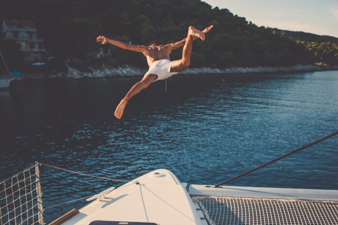 Mężczyzna skaczący do wody z jachtu