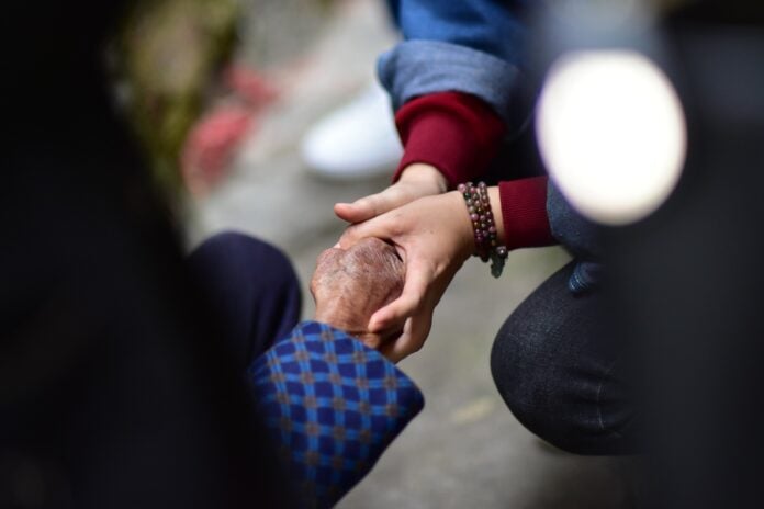 Młode dłonie trzymające dłonie starszej osoby