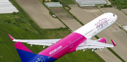 samolot Wizz Air lecący nad polami