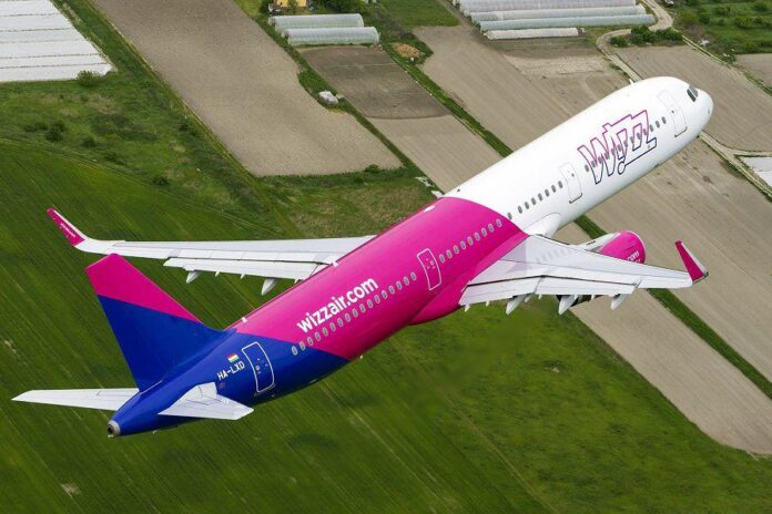 samolot Wizz Air lecący nad polami