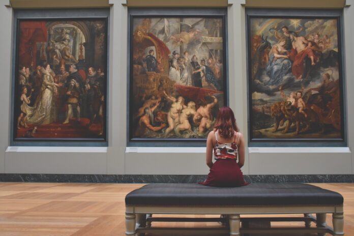 Kobieta siedząca w muzeum i patrząca na obrazy