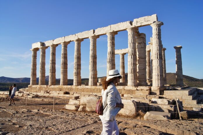 kobieta ubrana na biało na tle ruin starożytnej świątyni i niebieskiego nieba