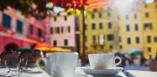 dwie filiżanki kawy, w tle włoskie miasteczko