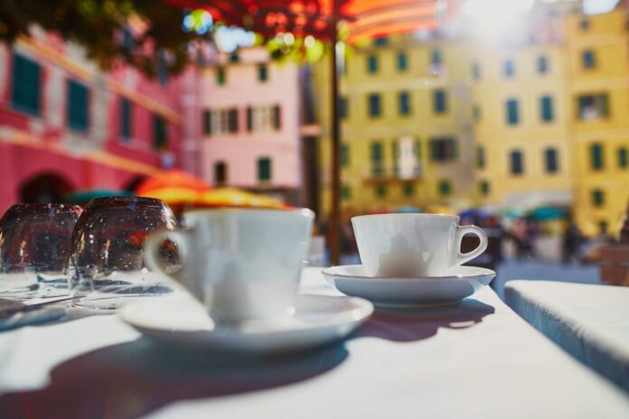 dwie filiżanki kawy, w tle włoskie miasteczko