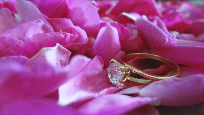 Pierścionek zaręczynowy leżący na płatkach róż