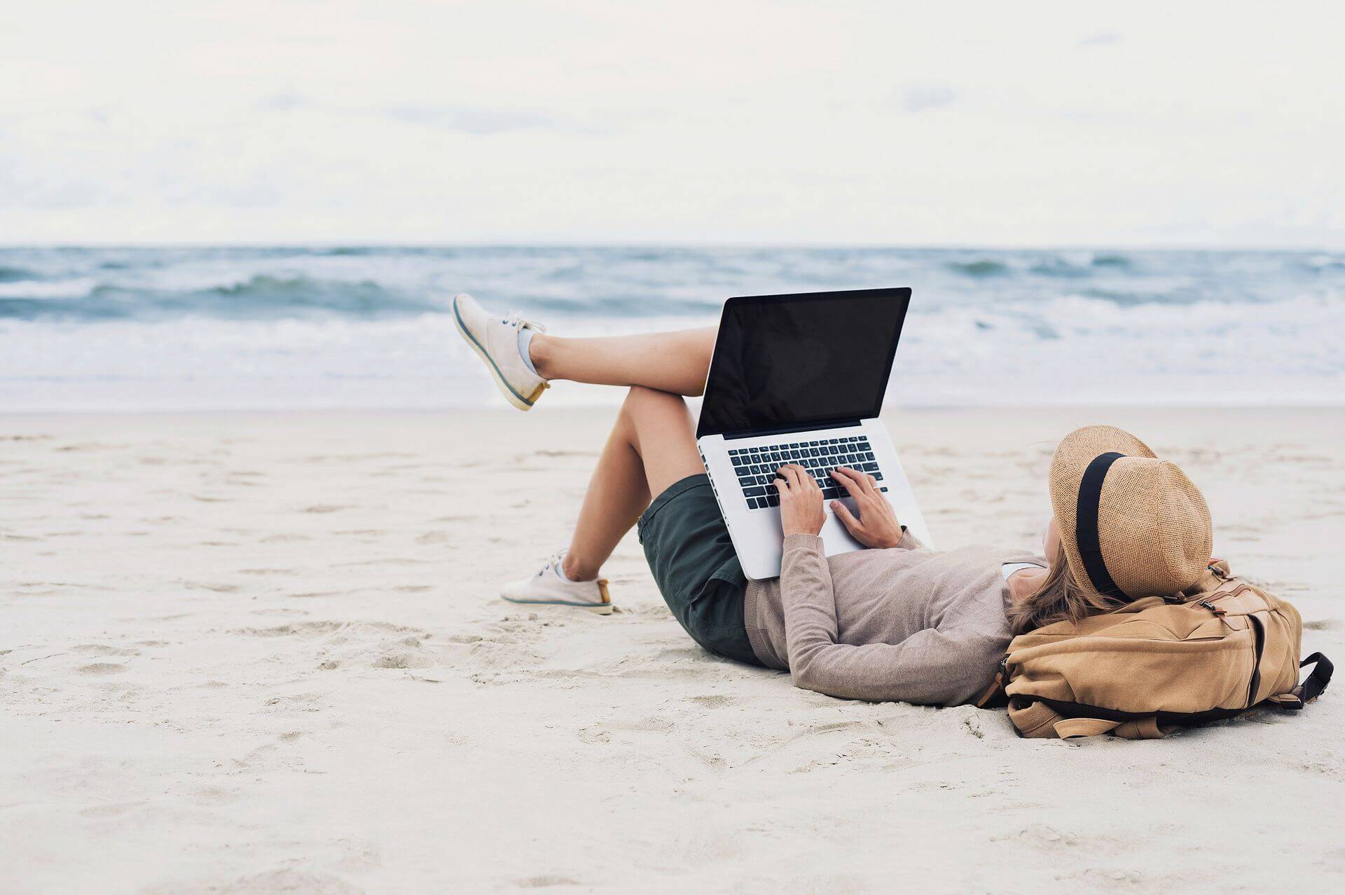 kobieta na plaży pracuje na laptopie