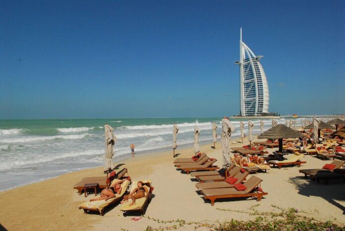 leżaki na plaży z wieżowcem w tle