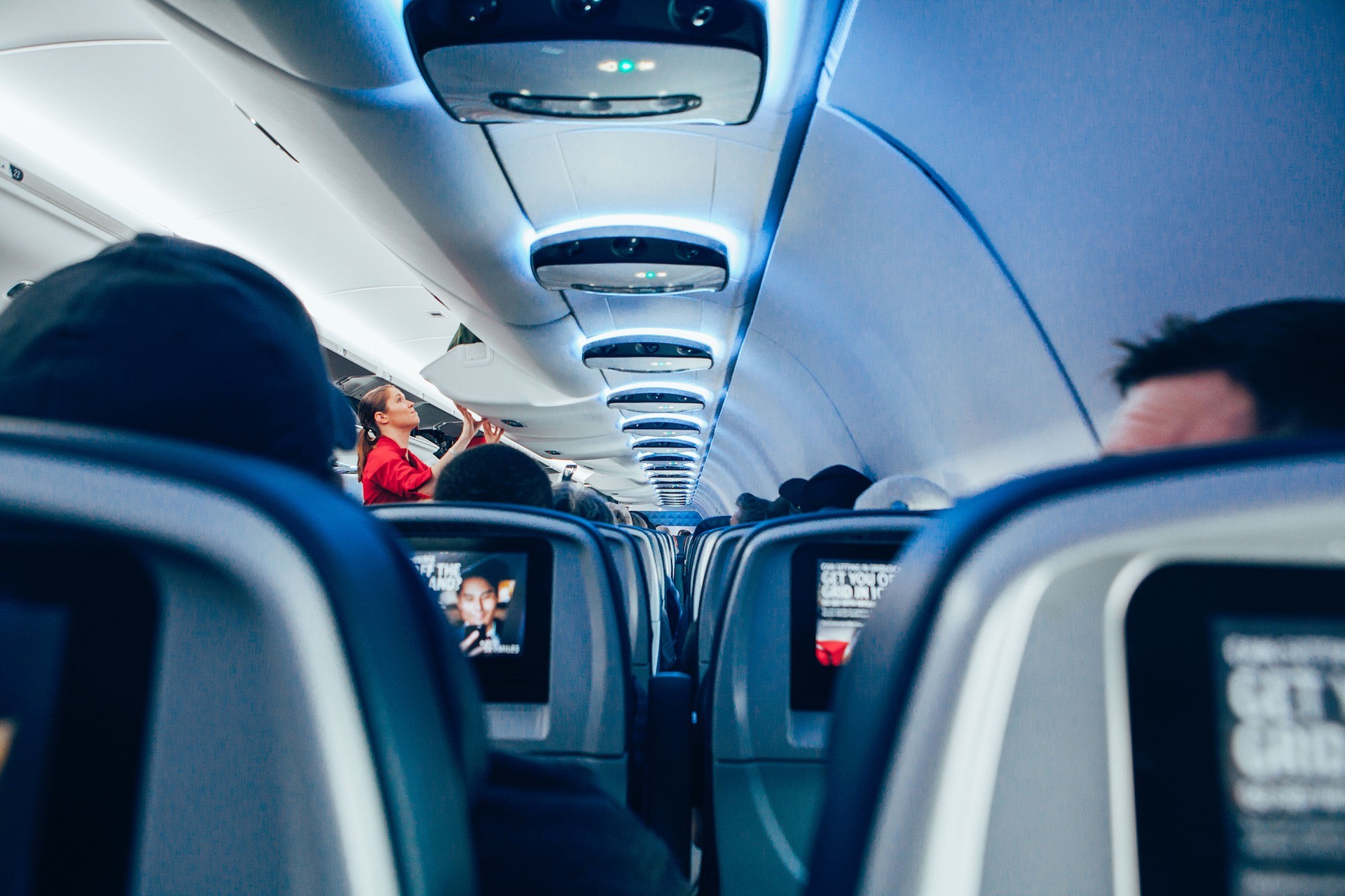 stewardessa pakuje bagaż do schowka nad głowami pasażerów
