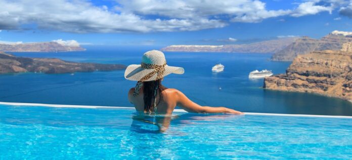 Kobieta relaksuje się w basenie, podziwiając widok na kalderę Santorini