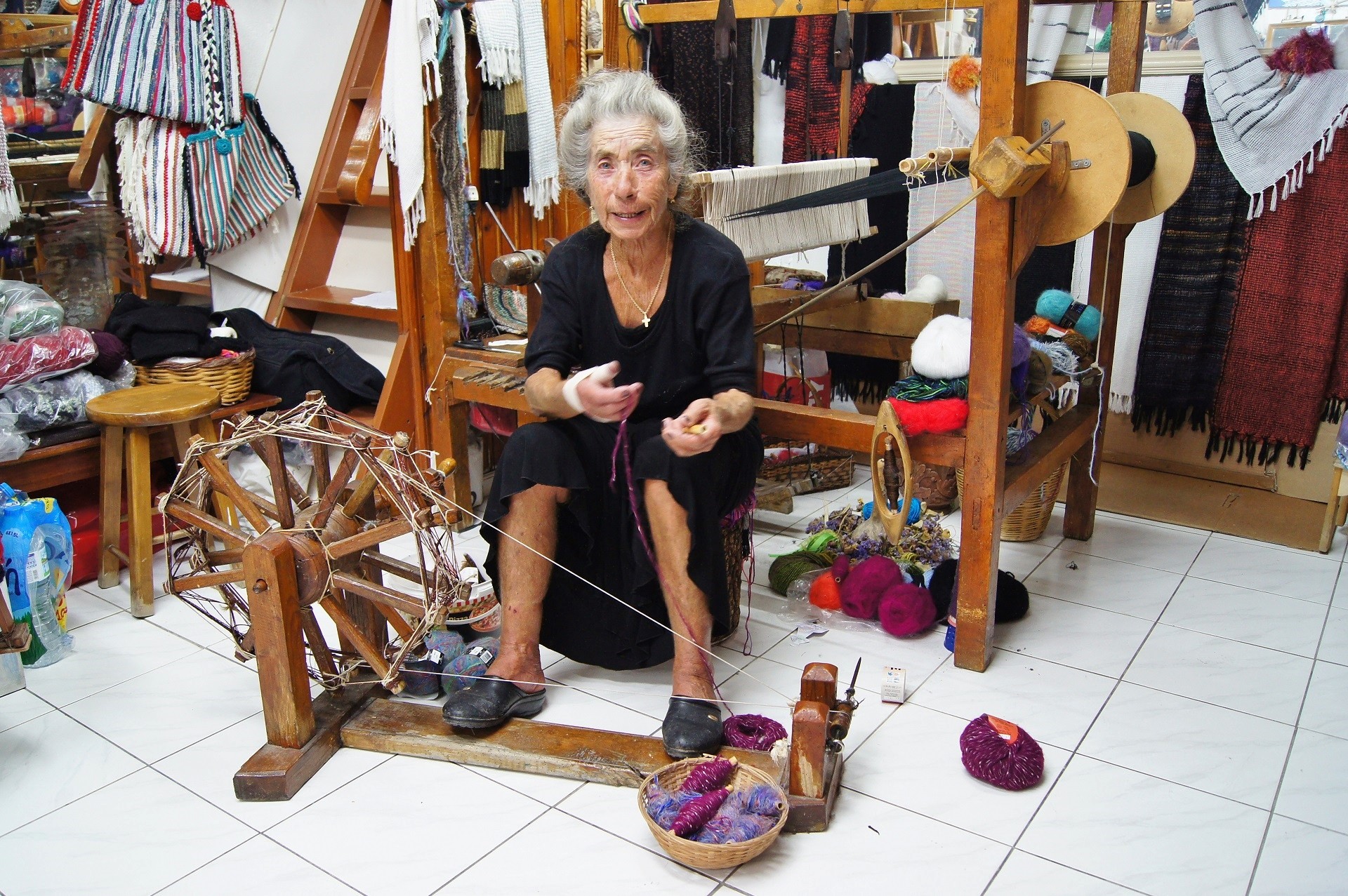 starsza kobieta w zakładzie pokazująca tradycyjny sposób tkania