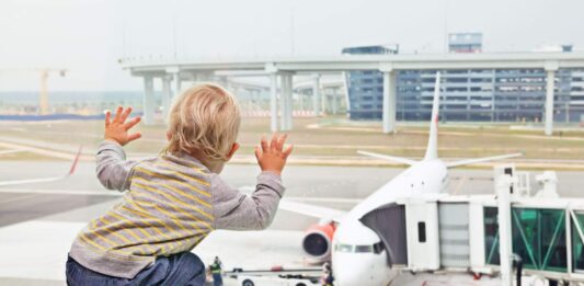 mały chłopiec patrzy na samolot przez szybę lotniska