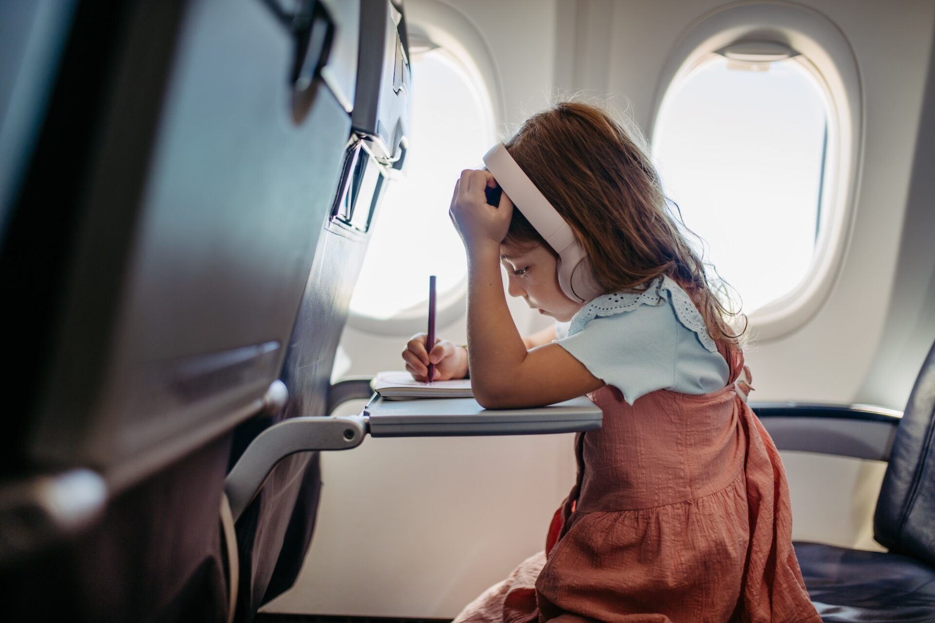 Little girl in airplane drawing and listening music.