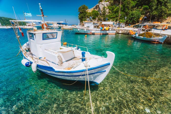 Traditional fishing boat in crystal clear Mediterranean sea cove of Ithaka island, Greece