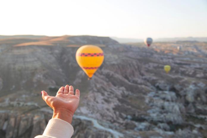 Womens hand against the background of flying balloons in the sky of Cappadocia. Holidays in Turkey