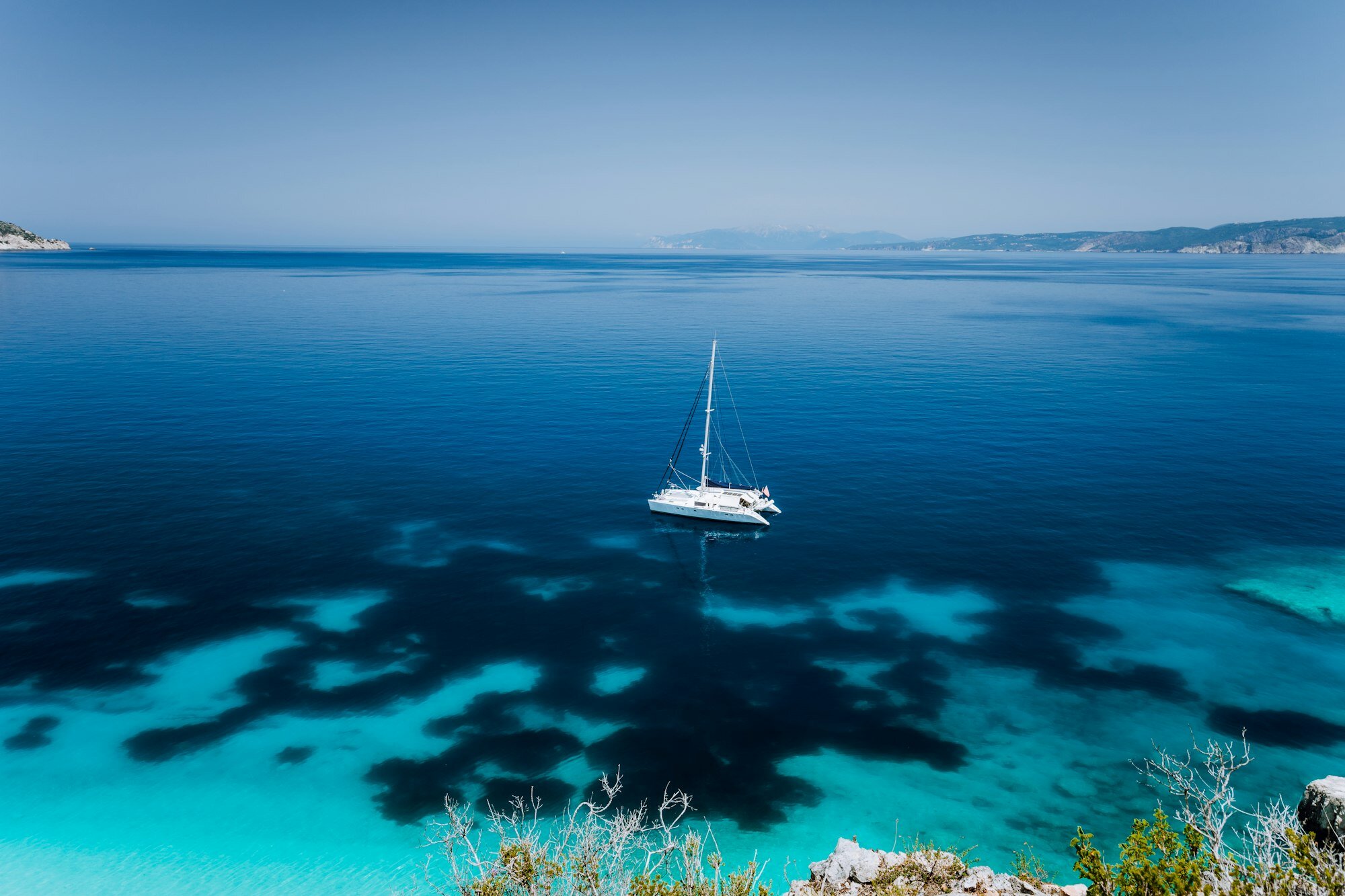 Fteri beach, Cephalonia Kefalonia, Greece. White catamaran yacht in clear blue transparent sea water