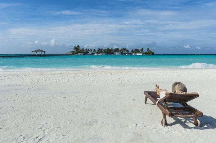 Maledives, Ari Atoll, Nalaguraidhoo, Sun Island Resort, back view of woman relaxing on the beach