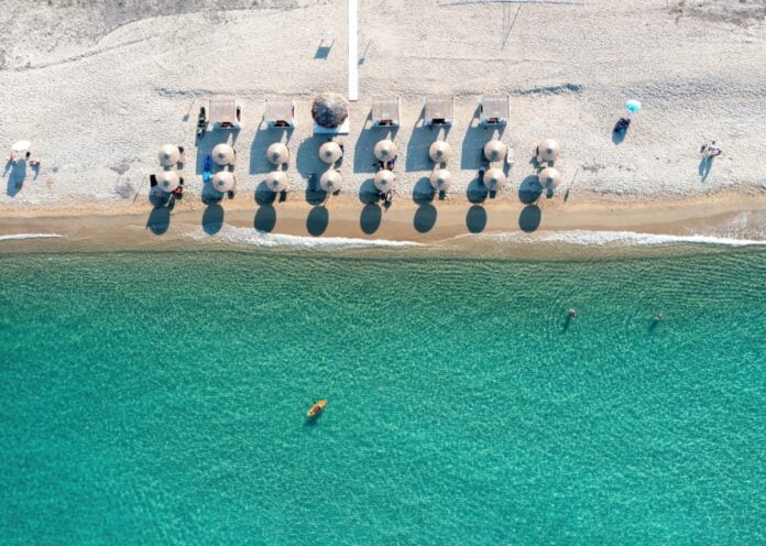 Greece, sandy beach, aerial view. People swim and relax at Chalkidiki. Sunny summer day