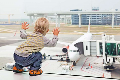 Little-baby-boy-waiting-boarding-to-flight-in-airport-transit-hall-and-looking-through-the-window-at-airplane-near-departure-gate.-shutterstock_316140362