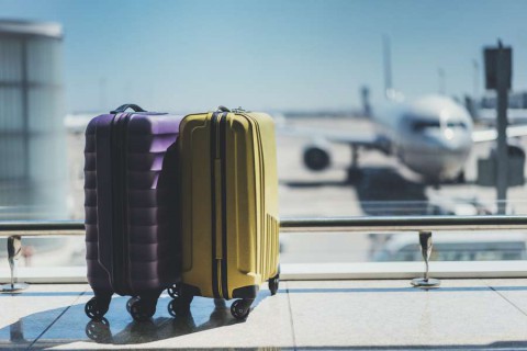 Suitcases-in-airport-departure-lounge-airplane-in-background-shutterstock_450980248
