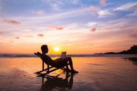 silhouette-of-happy-business-man-with-laptop-working-on-the-beach-shutterstock_377166919