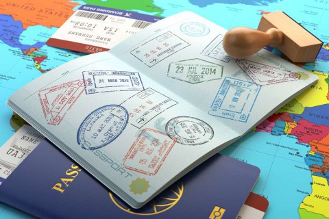 Opened-passport-with-visa-stamps-with-airline-boarding-pass-tickets-and-stamper-on-the-world-map.--shutterstock_397569799