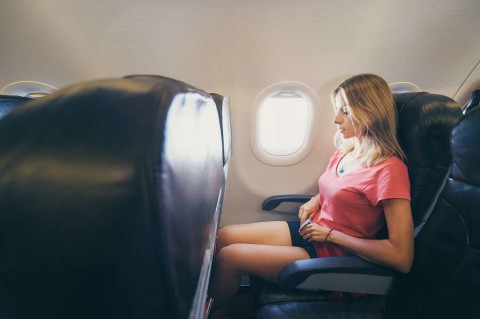 Safety-travel.-Young-woman-fasten-belts-while-sitting-in-airplane-seat-shutterstock_428320363-1