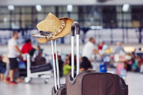 Airport-Luggage-with-straw-hat-at-the-airport-terminal-shutterstock_293900987-1