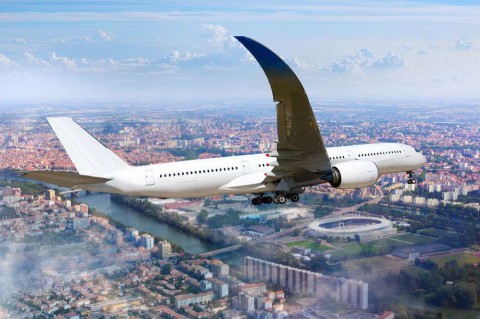 White-passenger-wide-body-aircraft-is-flying-in-the-cloudy-sky-over-the-over-city-residential-areas-the-river-and-the-stadium-shutterstock_406260157
