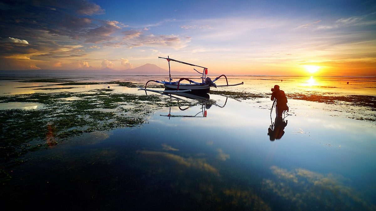Wschód słońca i tradycyjna łódź na plaży Sanur w Denpasarze